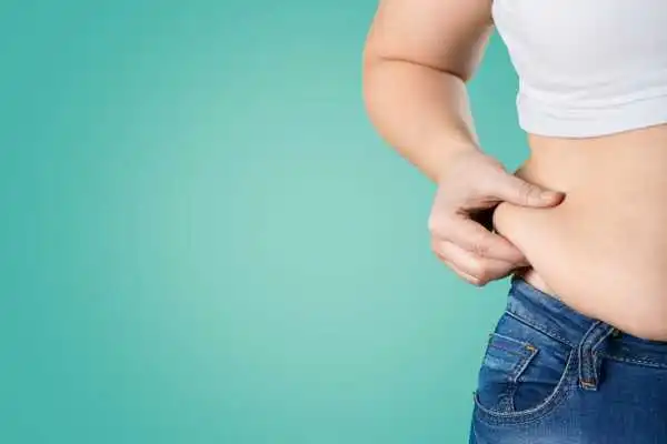Image of woman pinching her love handles to show weight gain Irthlingborough